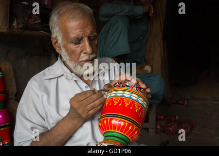 A carpenter is making colorful designs and flowers on leg of bunk in his shop in city of Pindi Bhatttian, Punjab , Pakistan. Stock Photo