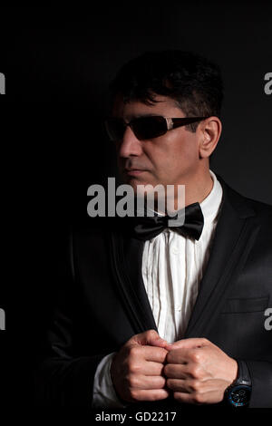 Business man in suit with sunglasses dresses butterfly on a black background Stock Photo