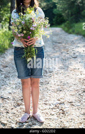 Woman hold bouquet of wildflowers in the forest. Stock Photo