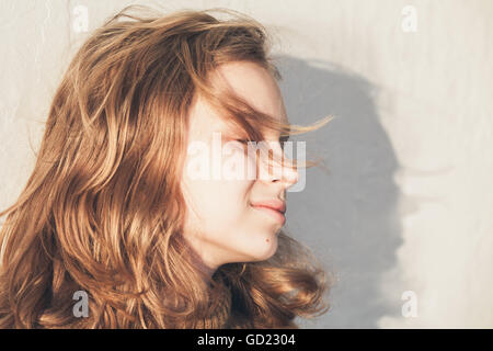 Beautiful happy blond teenage girl with closed eyes, close up outdoor portrait Stock Photo