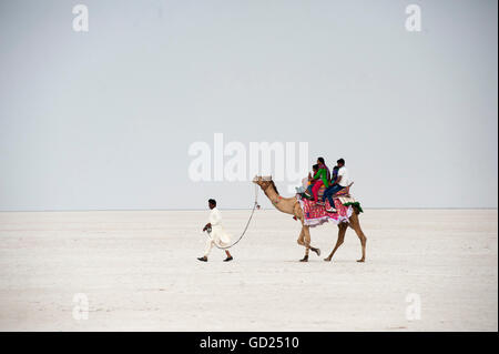 Indian family enjoying a camel ride in the white desert, a seasonal salt marsh in the Great Rann of Kutch, Kutch, Gujarat, India Stock Photo
