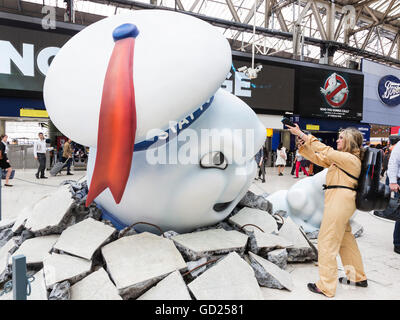 London, UK. 11 July 2016. Commuters came face-to-face with Mammoth Marshmallow Menace as Stay Puft smashes through the floor of Waterloo Station. The rebooted Ghostbusters movie makes its return to the cinemas 30 years after the release of the original film. Actress Faye Morrison, 31, poses to fight the creature. Stock Photo