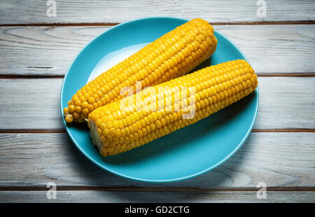 boiled corn on blue plate on white wooden background Stock Photo
