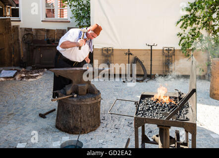 Friedberg, Germany - July 09, 2016: A man dressed in traditional costume is working as a blacksmith in the traditional way of th Stock Photo