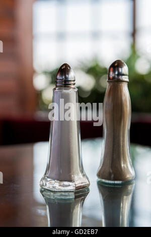 Ground salt and pepper shakers on a polished wood surface with light from a  window illuminating the table; rustic dining table with glass shakers Stock  Photo - Alamy