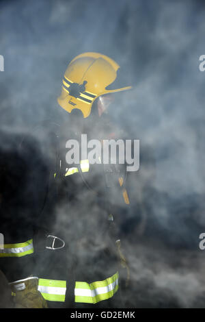 fire service. UK. Great Britain. Firefighter in smoke filled room Stock Photo