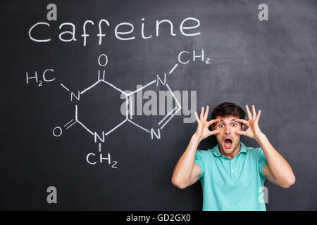 Funny crazy young professor of chemistry standing and shouting over chalkboard background Stock Photo