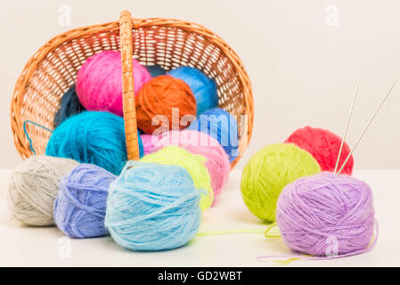 colored woolen thread crumbled from wicker basket close up on a white background Stock Photo