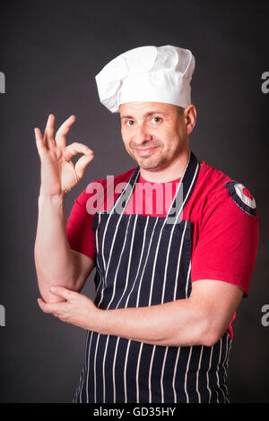 Portrait of cook with gesture okay in the studio on a black background Stock Photo