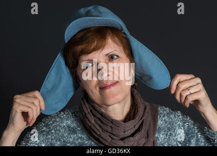 Indoor portrait of mature woman in blue cap being happy Stock Photo