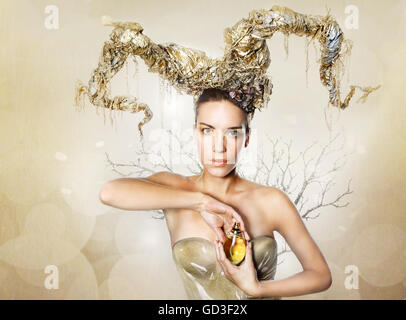 Mysterious woman in a gold horns and parfume bottle. Stock Photo