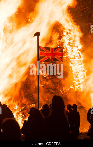Belfast, Northern Ireland. 11 Jul 2016 - A Union Flag flies in front of the traditional '11th Night' bonfire in the Lower Shankill Estate.