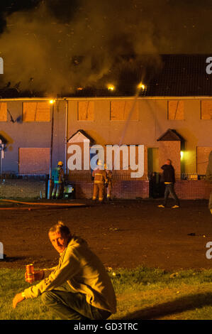 Belfast, Northern Ireland. 11 Jul 2016 - The Northern Ireland Fire and Rescue Service train a number of hoses on the roofs of a row of terraced houses after two houses were set on fire by the traditional '11th Night' bonfire. Credit:  Stephen Barnes/Alamy Live News