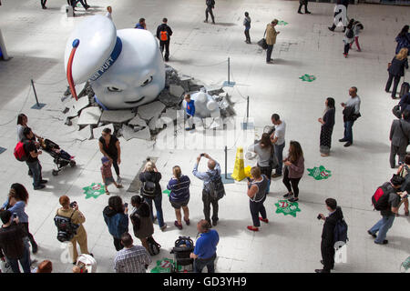 London, UK. 12th July 2016.   The Giant Marshmallow man breaking through the floor of Waterloo station  has become an attraction with crowds of commuters who stop to view and photograph the Ghosbusters film promotion Credit:  amer ghazzal/Alamy Live News Stock Photo