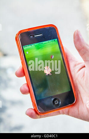 A young person uses an iPhone to play Pokémon GO, the latest augmented reality mobile app game to hit the worldwide app market. Stock Photo