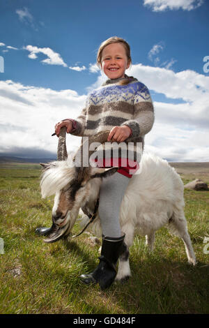 Girl sitting on a goat, Western Iceland Stock Photo