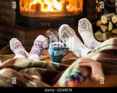 Warming and relaxing near fireplace. Mother and daughter holding hands in front of fire. Stock Photo