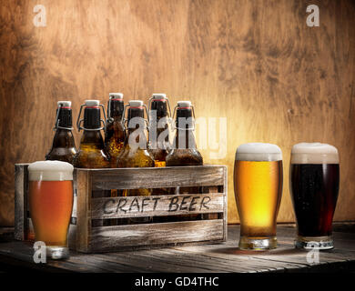 Crafting beer in bottles and glasses. On top of a wooden background. Stock Photo