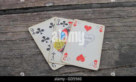 Three old playing cards on wooden background Stock Photo
