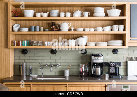 White crockery on custom-made open oak shelving by Bohemian works above Silestone worktop and coffee machine Stock Photo