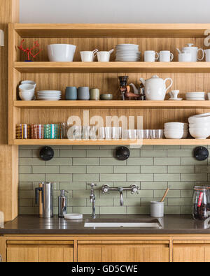 White crockery on custom-made open oak shelving by Bohemian Works above Silestone worktop and sink Stock Photo