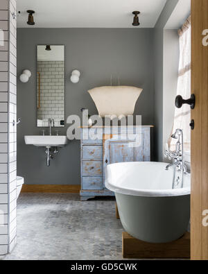 Free standing bath in bathroom with custom made cabinet by Bohemian Works and honeycomb flooring Stock Photo