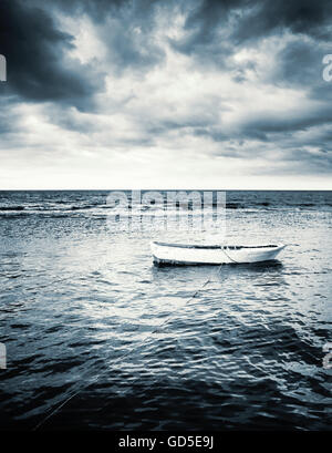 White wooden fishing boat under dramatic stormy clouds Stock Photo