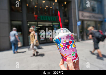 A Slurpee lover displays her free drink outside a 7-Eleven store in New York on Monday, July 11, 2016 (7-11, get it?), Free Slurpee Day! This year the chain is celebrating the 50th anniversary of the iconic slushy drink. The popular icy, slushy, syrupy drinks are available in regular and diet flavors, in combinations, and the stores have stocked up with extra barrels of syrup to meet the expected demand. The 87 year old chain expects to serve over 9 million Slurpees today. (© Richard B. Levine) Stock Photo