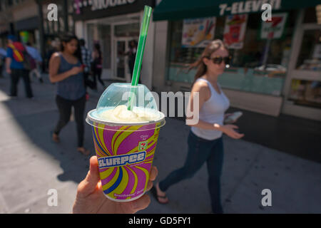 A Slurpee lover displays her free drink outside a 7-Eleven store in New York on Monday, July 11, 2016 (7-11, get it?), Free Slurpee Day! This year the chain is celebrating the 50th anniversary of the iconic slushy drink. The popular icy, slushy, syrupy drinks are available in regular and diet flavors, in combinations, and the stores have stocked up with extra barrels of syrup to meet the expected demand. The 87 year old chain expects to serve over 9 million Slurpees today. (© Richard B. Levine) Stock Photo