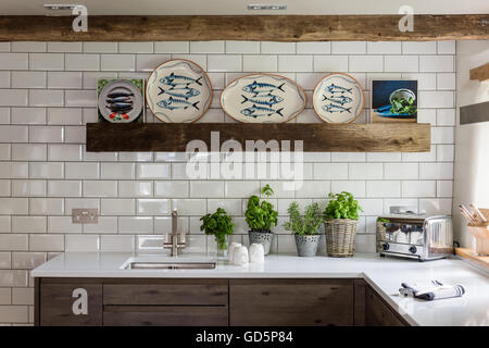 Decorative fish plates by Wendy Bray in kitchen with white metro wall tiles, Silestone worktops and wooden ceiling beams Stock Photo