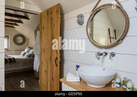 Painted white wooden planks and nautical style mirror in ensuite bathroom Stock Photo