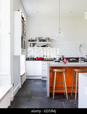 High ceilinged kitchen with white metro tiles and grey riven slate floor. Stock Photo