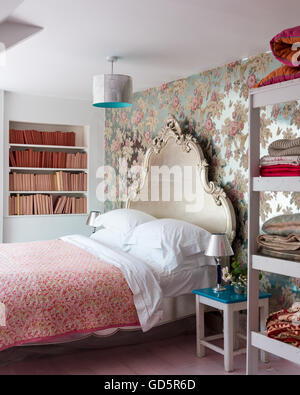 Silver foil floral wallpaper by Anna French in bedroom with ornate carved silverleaf bed and vintage french quilt. Stock Photo