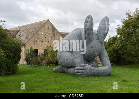 'Lady Hare' by Sophie Ryder crouched on lawn in front of converted cottage Stock Photo