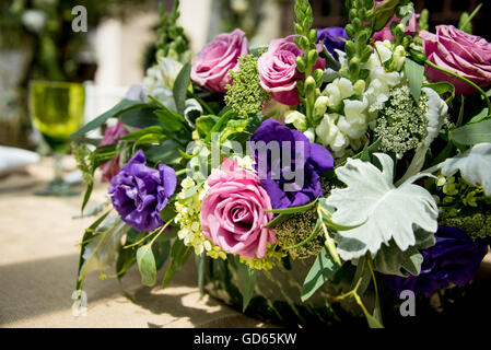 Floral table centerpiece at a wedding reception with an arrangement of pink and purple roses amongst assorted white flowers and Stock Photo