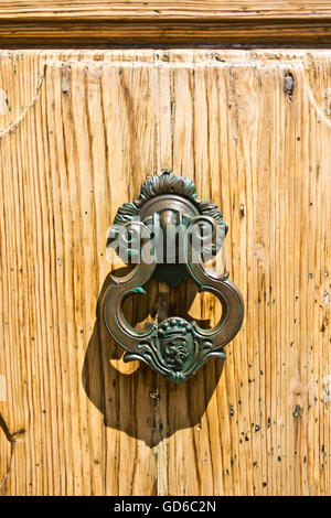 Wrought iron knocker craftsmanship of ancient historical building in the wooden door Stock Photo