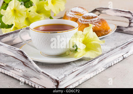 Breakfast Danish pastry and cup of tea on vintage  serving tray. Sweet cinnamon rolls and tea cup with yellow flowers. Breakfast Stock Photo