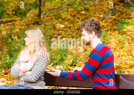 Conflicts in relationship. Arguing and discussing problems. Understanding feelings. Young couple sit in park having a conversation. Stock Photo