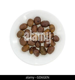 Top view of a plate with organic whole shelled roasted chestnuts isolated on a white background. Stock Photo