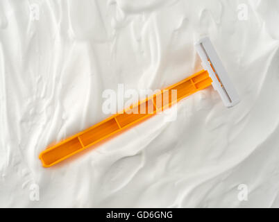 Top view of a generic disposable shaving razor that has fallen into shaving foam. Stock Photo