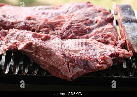 Raw Beef Meat on the Grill, Close Up. Sinta, Raw meat, raw flesh. Red meat on the grill. Rare sinta, fresh salted asado at the beginning of the holida Stock Photo