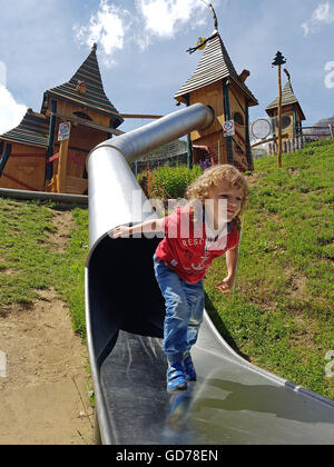Boy happily playing on a playground in the mountains Stock Photo