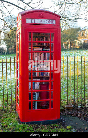Red telephone box being used as a library in a village in England. Stock Photo