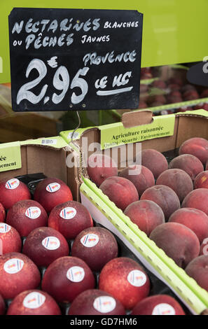 Fresh nectarines and peaches for sale against a striking green background.  Boulogne-sur-Mer, France Stock Photo