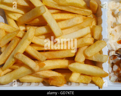 Close-up of golden french-fried potato chips in a white plastic dish with mayonnaise Stock Photo