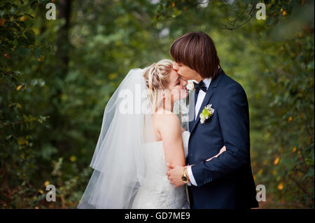 The groom kisses the bride at a wedding in the woods Stock Photo