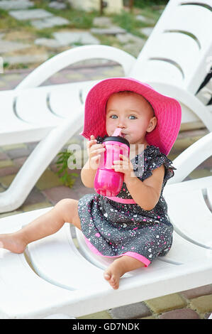 little girl in red hat sits on a lounger Stock Photo