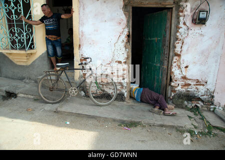 A Cuban man lies drunk and asleep in the doorway to his rundown house in a poor neighbourhood of Trinidad Cuba Stock Photo