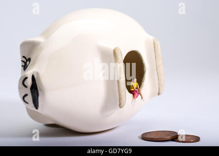 concept image of a lone figure with an empty piggy bank to illustrate low savings and low interest rates on savings Stock Photo