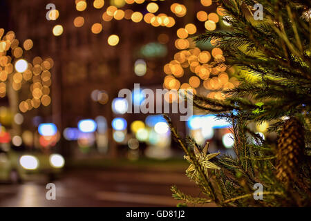Branch of decorated Christmas tree in late evening on the street with night illumination Stock Photo